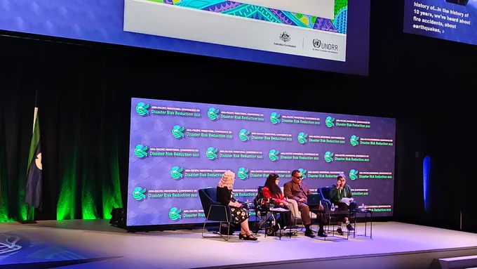 Four panelists speaking at the stage of spotlight event APMCDRR 