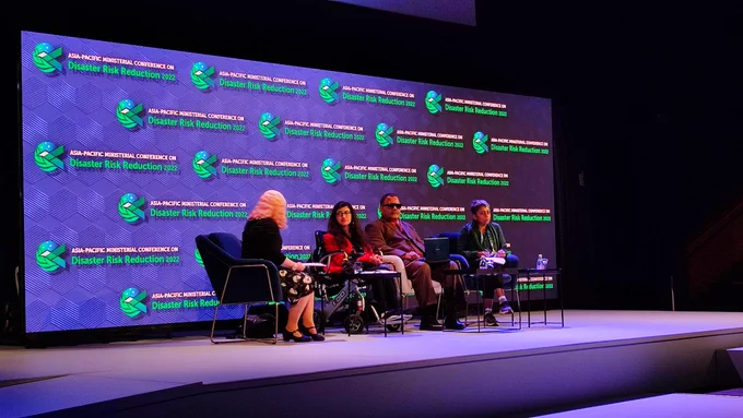 Panelists speaking at the stage of spotlight event at APMCDRR 