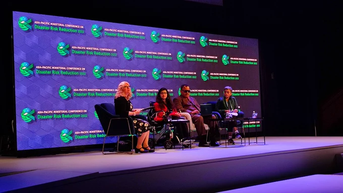 Four panelists speaking at the stage of spotlight event of APMCDRR 