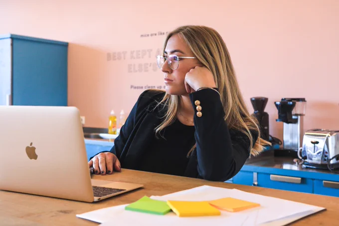 A working woman is in reflective mood, sitting at her work station looking into the distance. Photo by magnet.me on unsplash