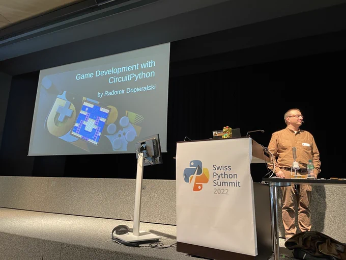 Radomir standing at the lectern in front of his slides on Game Development with CircuitPython.