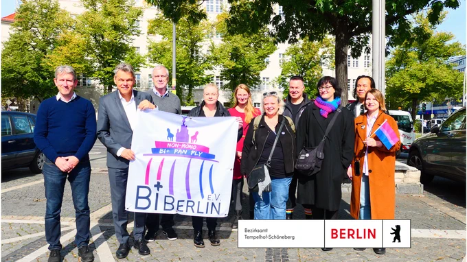Gruppe von Menschen steht vor dem Rathaus Schöneberg zur Hissung der bi-Flagge. Der Bezirksbürgermeister ist auch dabei.
