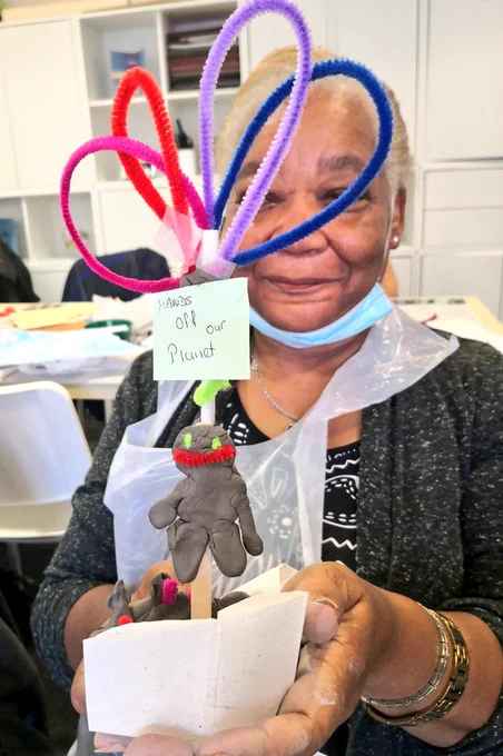 A black woman holding a sculpture made from clay and recycled materials 