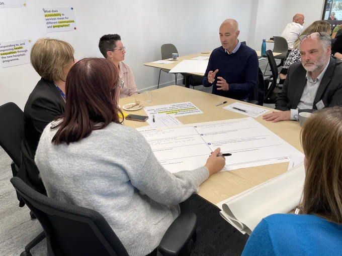 A group sat around a table write ideas on digital sustainability