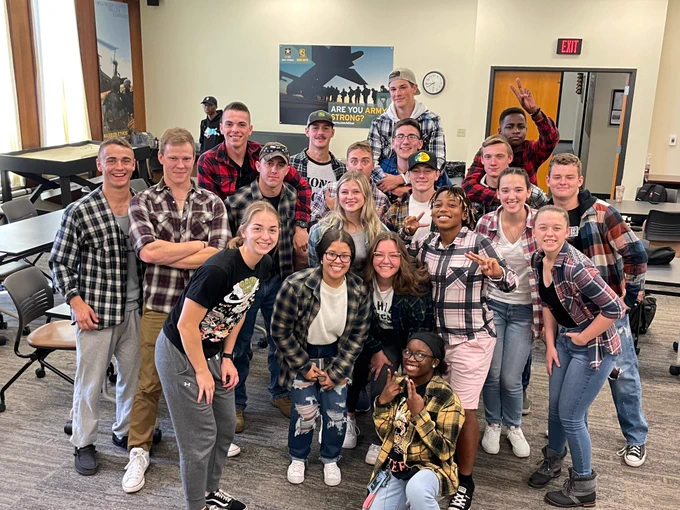 A group of students wearing flannel shirts smiles at the camera. 