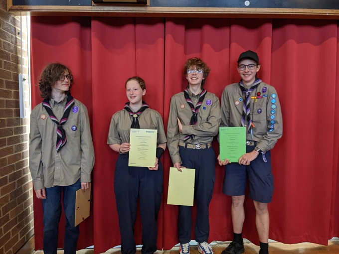 Four Explorer Scouts standing in a line holding their award certificates. 