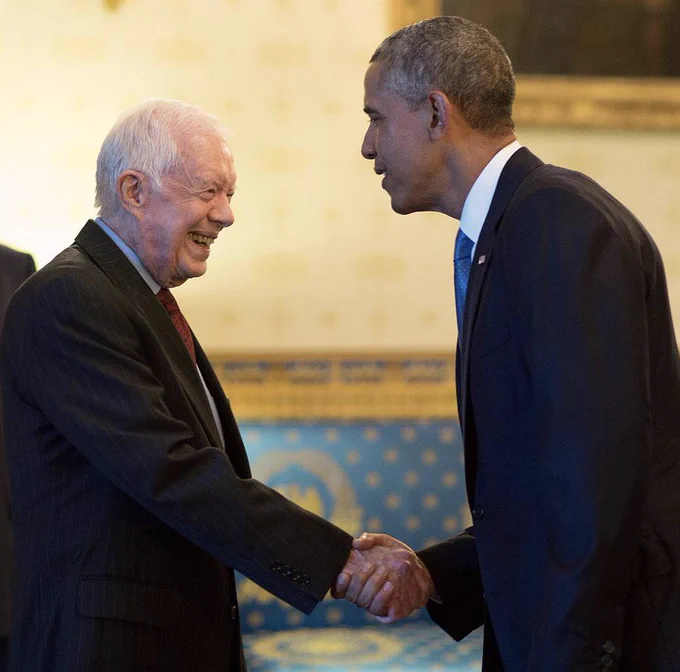 President Carter and President Obama shake hands in the Blue Room of the White House.
