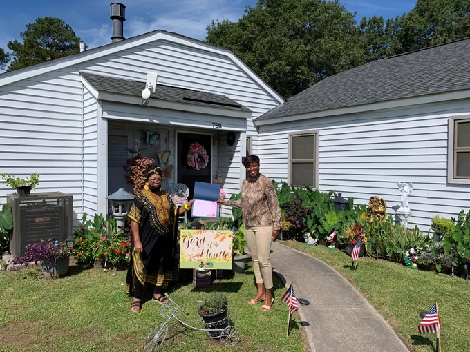 Yard of the Month winner Marie Hill is outside in her front yard, receiving her certificate from HACG Staff Member Sharita Oates.  