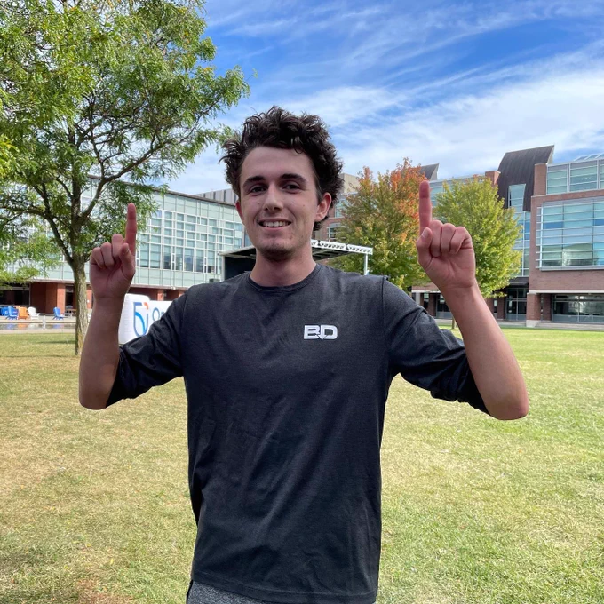 Jay holds his index fingers up in the air to make the number one as he is first to cross the finish line.