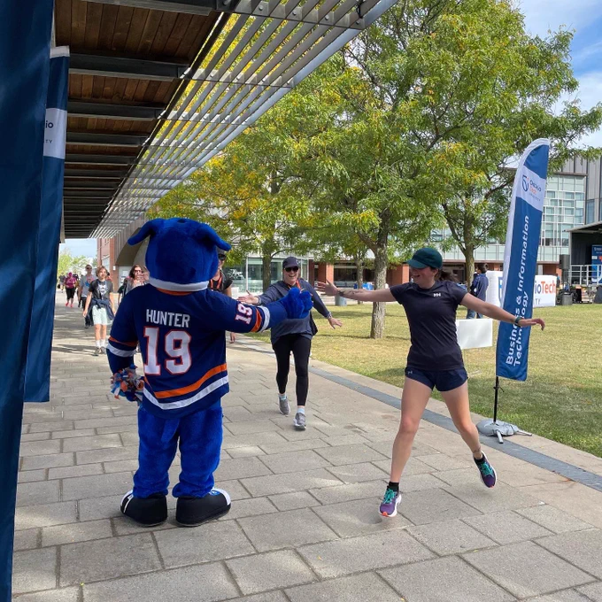 Participants give Hunter the Ridgeback a high five as they cross the finish line