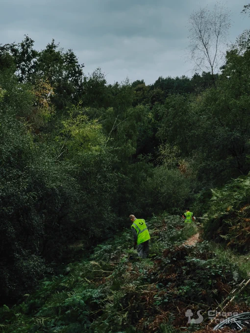 Two volunteers working on the trail on a hillside.