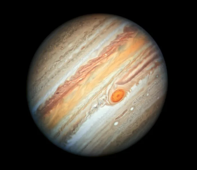 Jupiter as seen by Hubble. Its bands and zones are clearly visible, seen as stripes running across the planet in shades of brown, white, and orange, and the Great Red Spot dominates the southern hemisphere and appears as a red dot in the image.