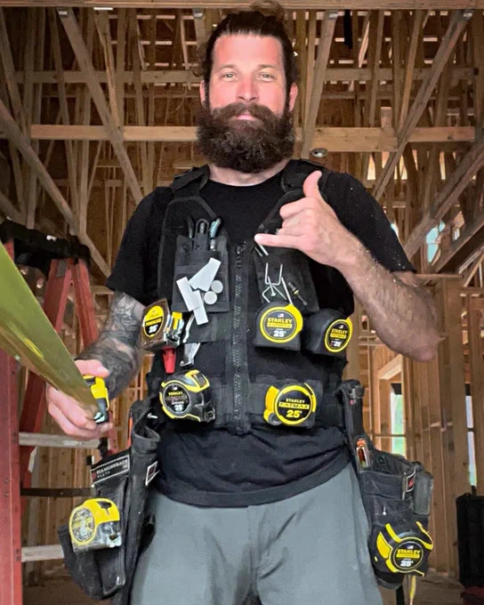 A Pro wearing seven different STANLEY® tape measures on his tool vest and holding an additional tape in his hand.
