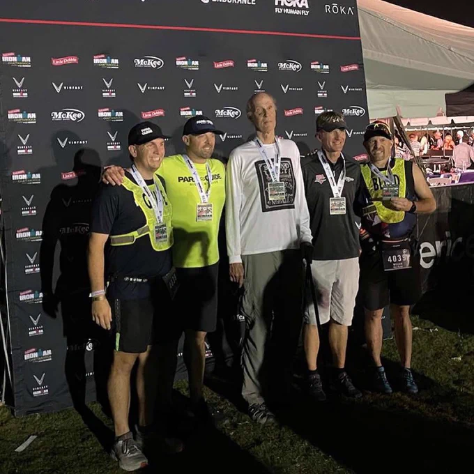 The relay team is gathered after the race finish in front of the official backdrop