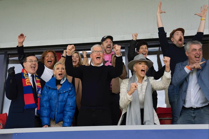 Tim cheers with other Apple executives and the stars of Ted Lasso on Apple TV  at the AFC Richmond stadium.