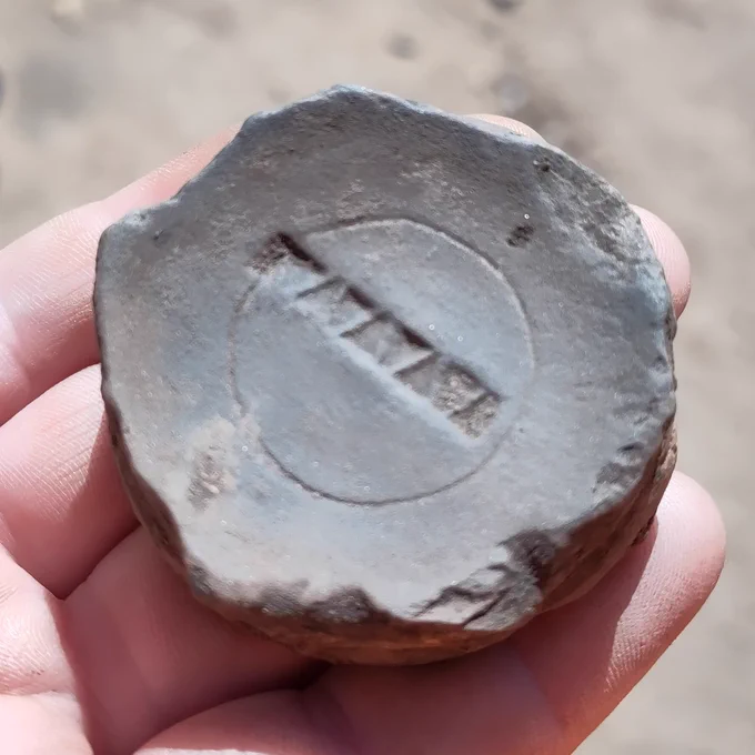 Inner surface of grey pot base stamped with a row of small triangles within a thin circle