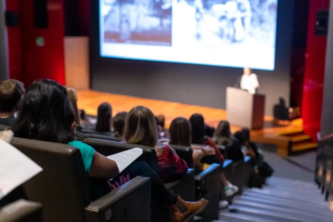 View from the back of lecture theatre looking at the presenter who is blurred 