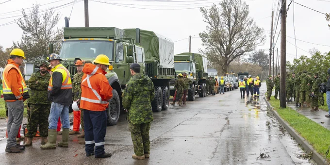 CAF members stand in front of military trucks.