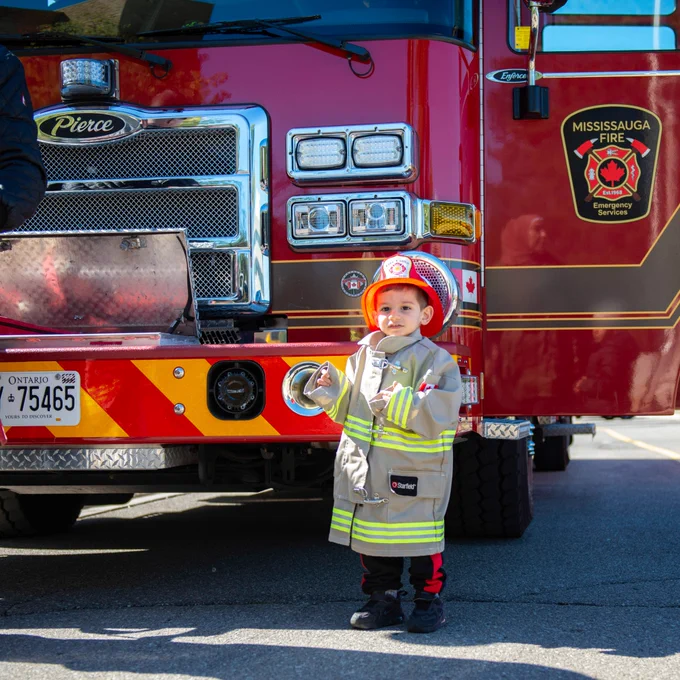 Photo of a small boy with a firefighter uniform on.