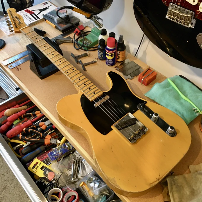 A blonde Fender Telecaster electric guitar on a workbench for a service and string change at Guitar Bath, England