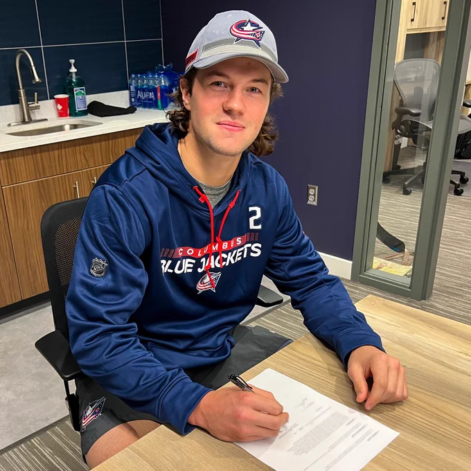 Andrew Peeke signs his 3 year contract in a kitchen. 