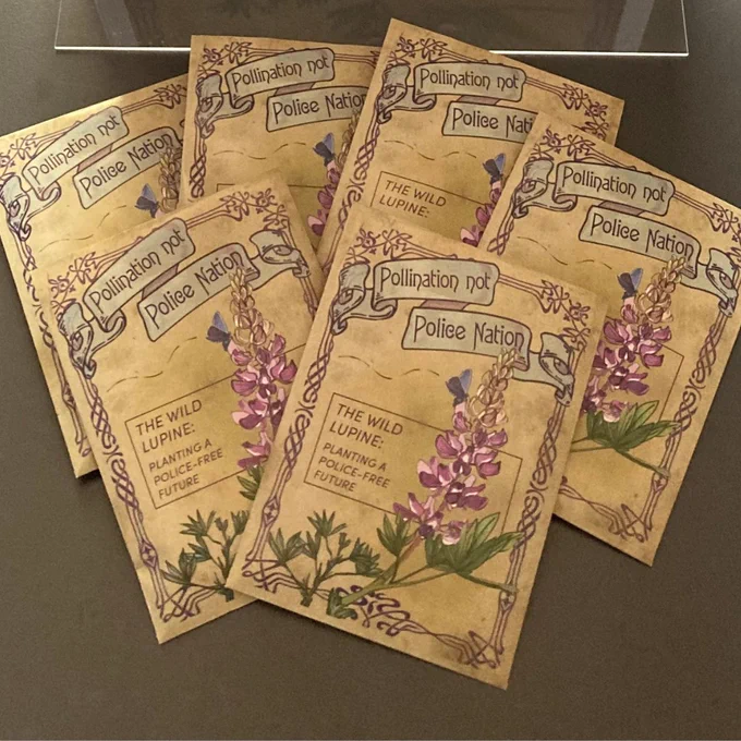 a photograph of six seed packets; text on them says "pollination, not police nation: the wild lupine: planting a police-free future"   an image of a lupine