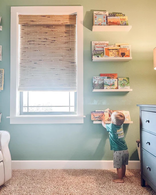 A toddler standing by a window inside a child's room