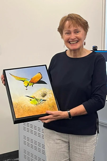 Jill holds a painting of birds