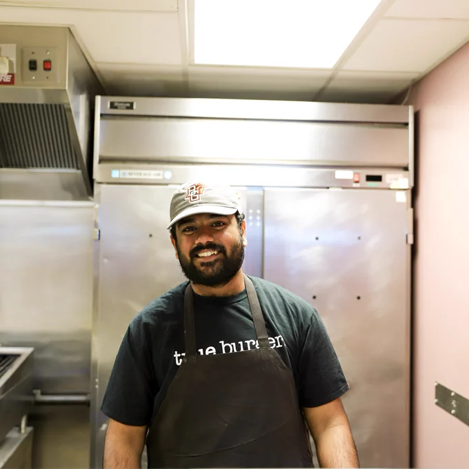 A man stands in front of a steel door. He is smiling at the camera. 