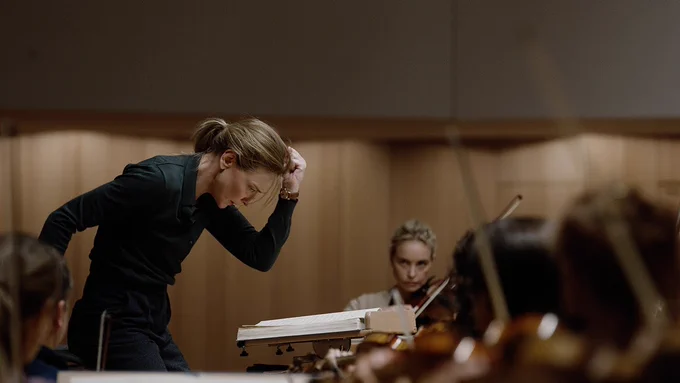Cate Blanchett conducting orchestra, with one arm held to her forehead in concentration