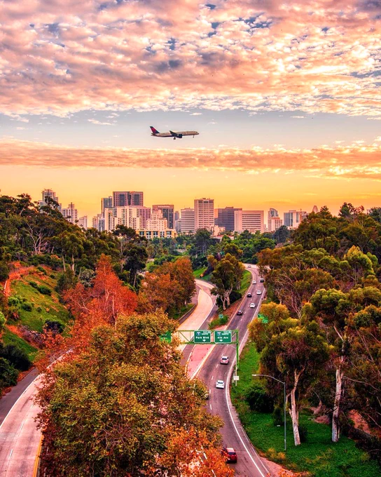 An airplane flying over a freeway at sunset in San Diego