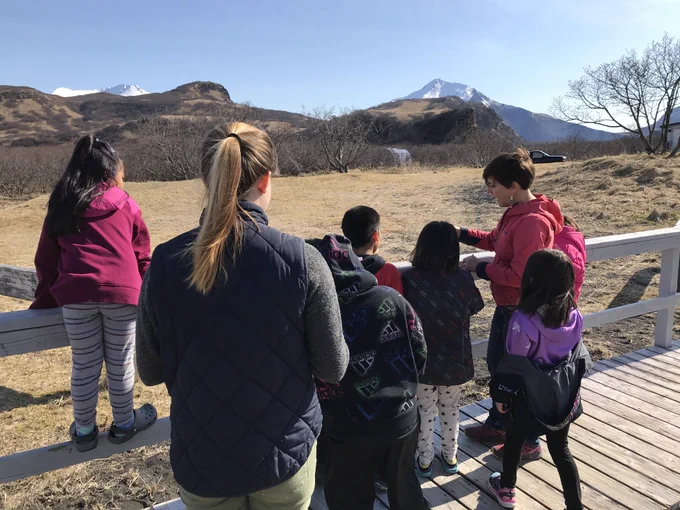 AVO scientist talking about Mt. Veniaminof volcano with students from Perryville school. The volcano is visible in the distance.