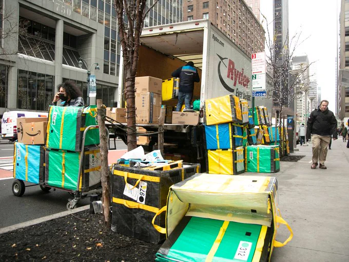 Packages and delivery carts piled up next to a truck. 