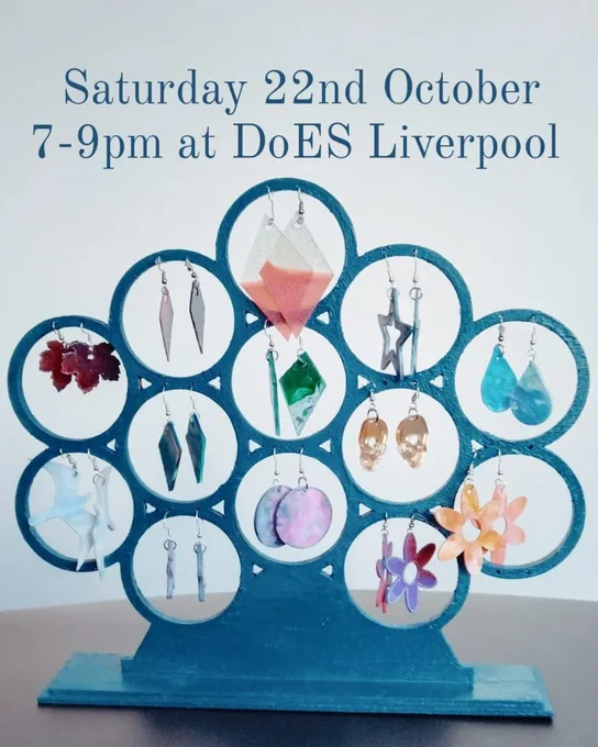 Picture shows a blue jewellery stand with different styles of colourful recycled plastic earrings (diamonds, leaves, flowers...).
The text says "Saturday 22nd October 7 - 9pm at DoES Liverpool"