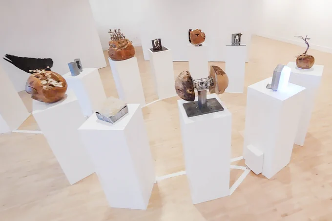 in an overview image, ten pedestals with individual pieces of art atop them are visible. they are a mixture of metal and wooden pieces with wings, trees, lights protruding from them.