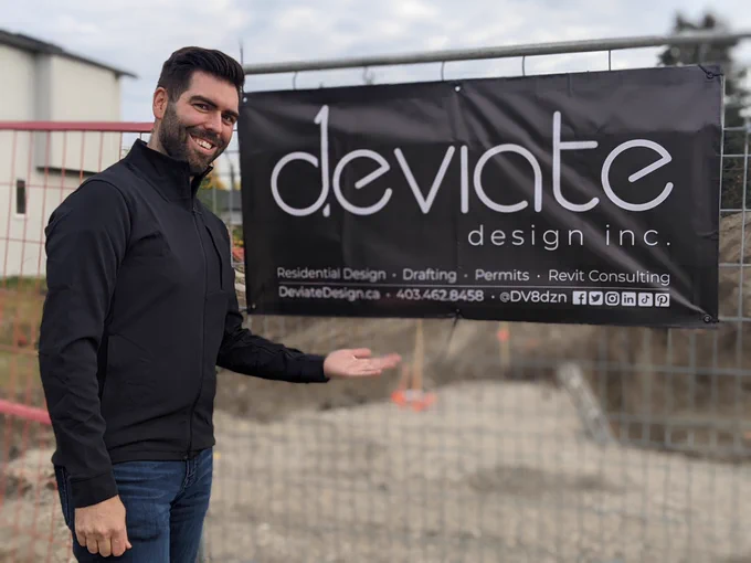 Tom proudly displays the Deviate Design Inc. site sign attached to the construction fence at the North Glenmore Park construction site for a new semi-detached infill.