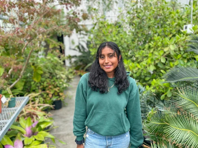 Woman with a green shirt standing in a room full of plants! 