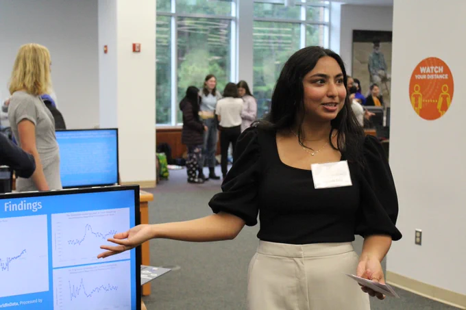 A W&M student sharing his research research project with a peer.