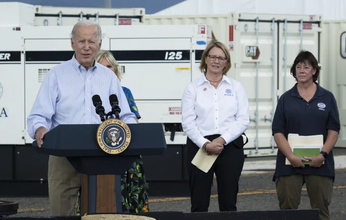 President Biden stands at a podium in Puerto Rico. Two people are to his right.