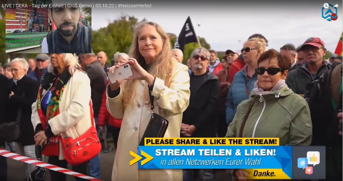 Die Großkundgebung von Geraer Nazis, Querdenker*innen und AfD am 3.10.2022 in Gera: In der ersten Reihe vor der Bühne steht Marion Schneider, Geschäftsführerin der Toskana Therme Bad Sulza. Im Hintergrund sind "Widerstand"-Flaggen der Naziszene zu sehen.