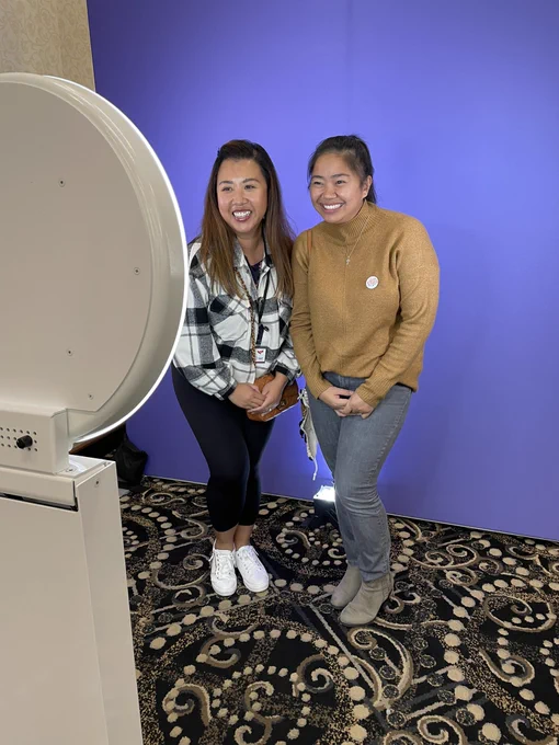Two individuals taking a photo at the photo booth at the conference