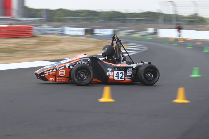 University of Adger's black and orange car prepares to take a corner on the sunny Sprint Course during Formula Student 2018 on Copse Corner at Silverstone.