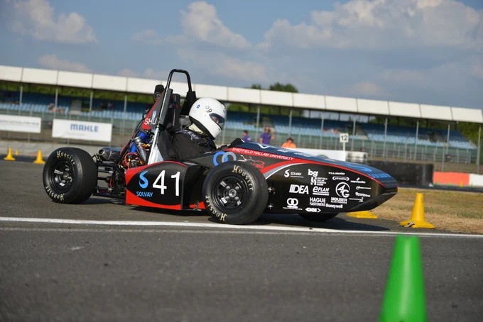 Sheffield Hallam University's red and black car rounds a bend on the sunny Sprint Course during Formula Student 2018 on Copse Corner at Silverstone.