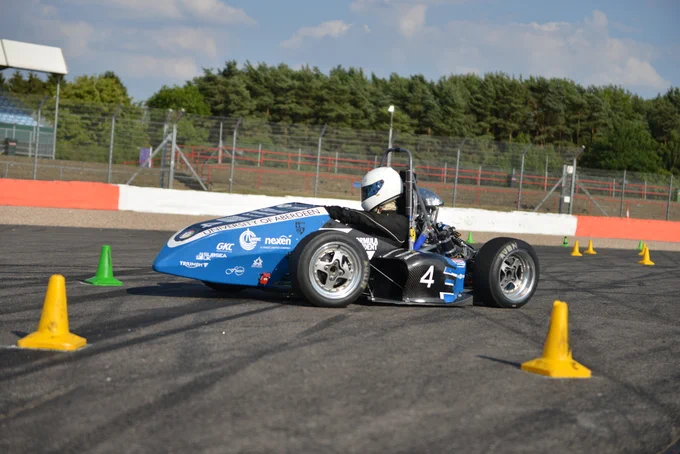 University of Aberdeen's blue and black car rounds a bend on the sunny Sprint Course during Formula Student 2018 on Copse Corner at Silverstone.