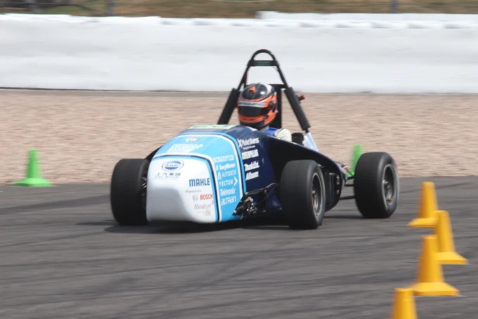 University of Bath's white and blue electric car speeds round a bend on the sunny Sprint Course during Formula Student 2018 on Copse Corner at Silverstone.