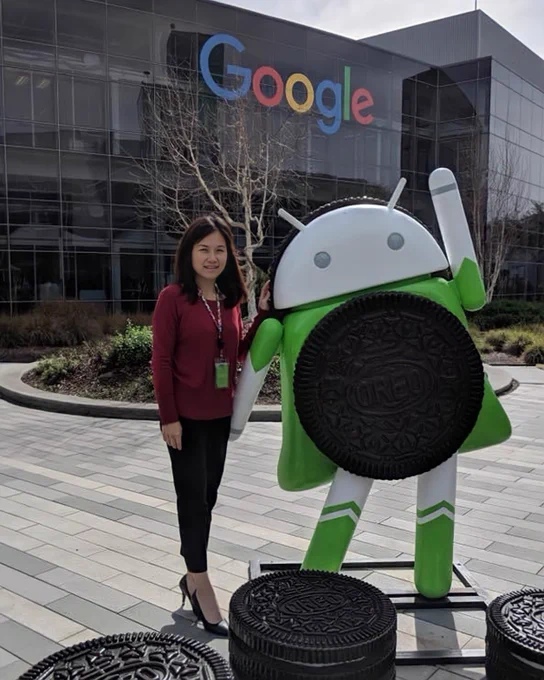 Frances standing in front of a stage with a Made by Google sign and a big screen. She’s wearing a headset. There are white chairs lined up behind her.