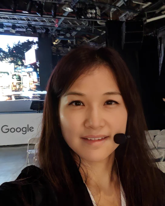 Frances standing outside a building with “Google” written on the outside of it, standing next to the Android character.
