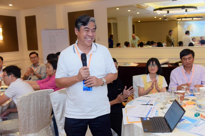A guest holds a microphone among other attendees at an event table