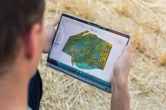 A persona holding a tablet in a rural setting