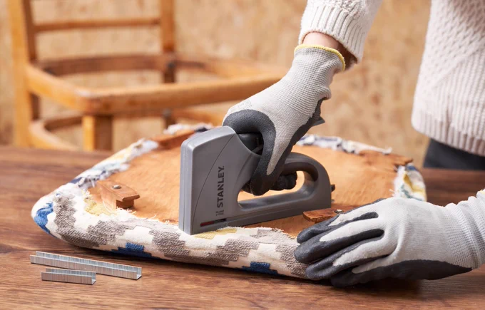 A Pro using the Light Duty Staple Gun to tack down fabric onto a seat cushion. 